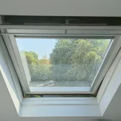 Fenêtre de toit vue de l’intérieur, vitre couverte de traces et de projections avant nettoyage